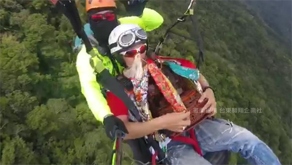堂主緊抱劉部大帝搭上飛行傘，進行獨特的空中遶境祈福儀式。圖：台東翱翔企業社提供