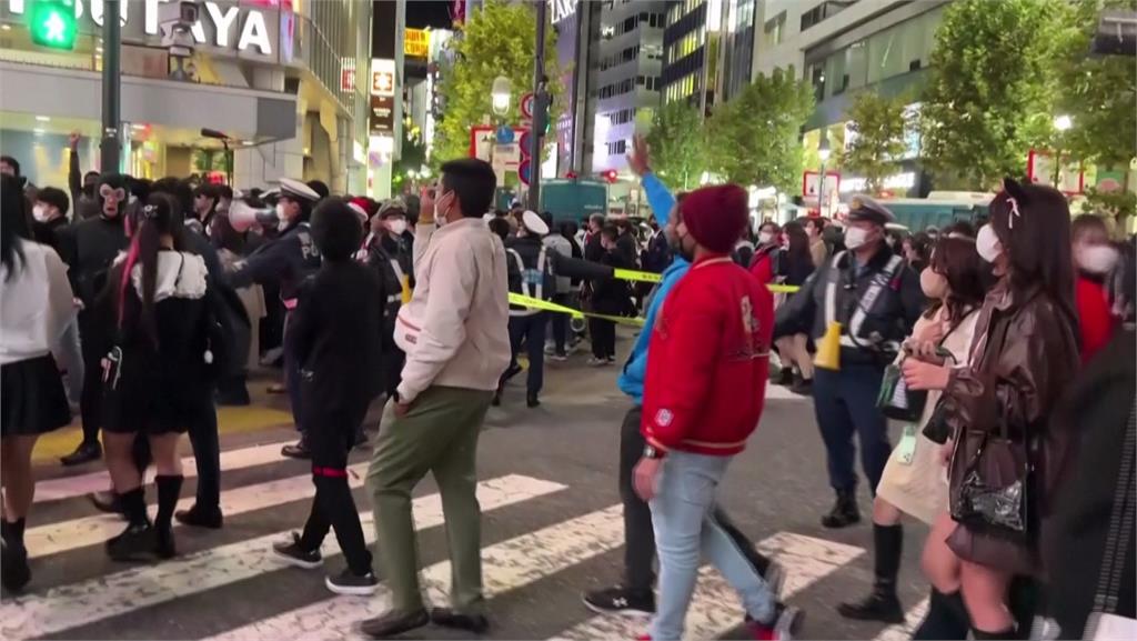 東京澀谷人潮湧現，後方警察圍成人鍊。圖／美聯社、路透社、NHK