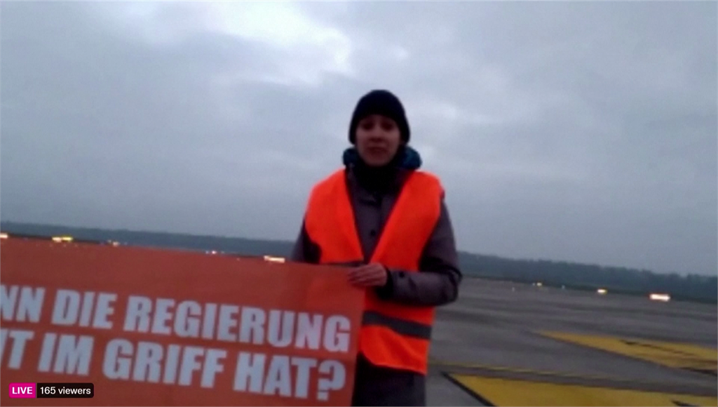 德國環保人士把手黏在飛機跑道上抗議。圖／路透社