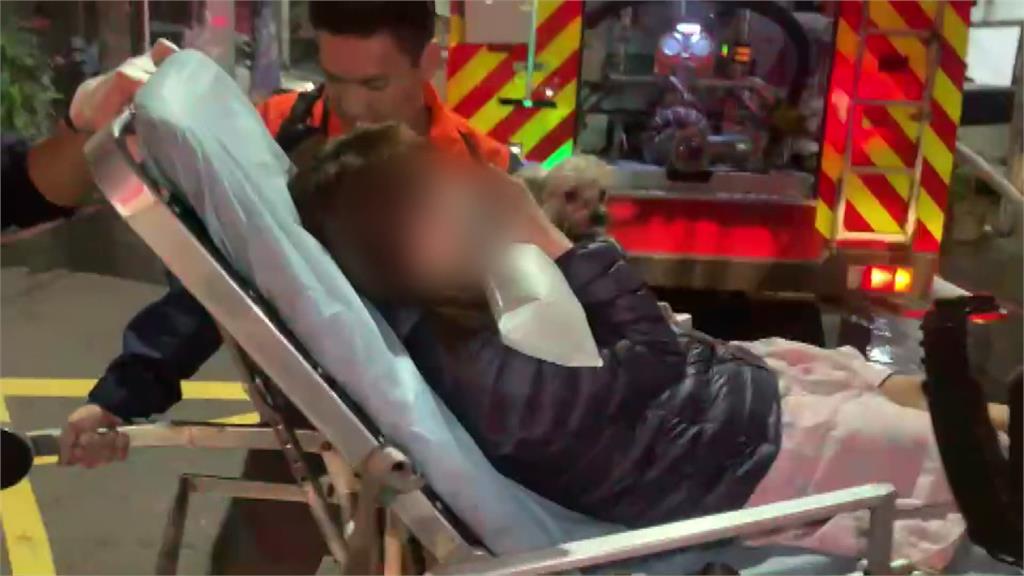 女子從火場脫困被送上救護車，仍緊抱著愛犬。圖：台視新聞