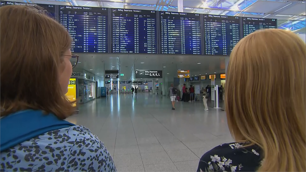 旅客們抬頭看著機場內的電子看板，發現沒有飛機可以搭。圖／美聯社、路透社、CNN