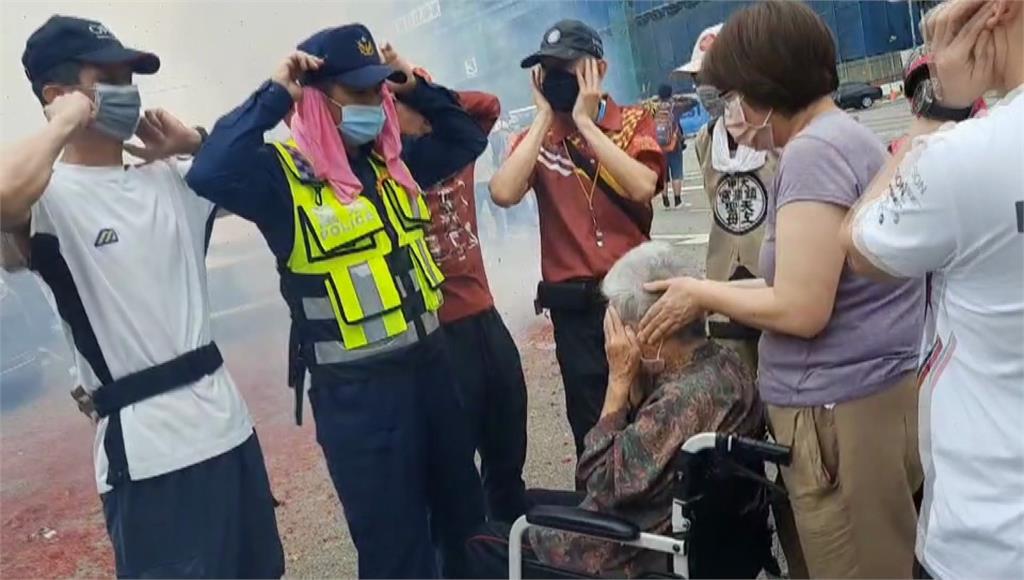 88歲的王姓阿嬤由警方、民眾協助肉身擋鞭炮。圖／台視新聞