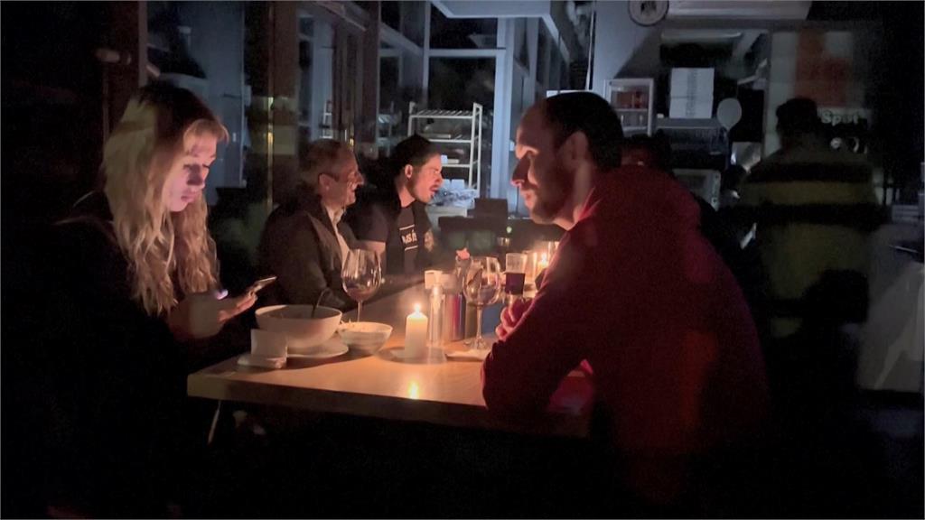 基輔市中心餐廳一片黑暗，服務生為顧客點起蠟燭。圖／美聯社＋路透社