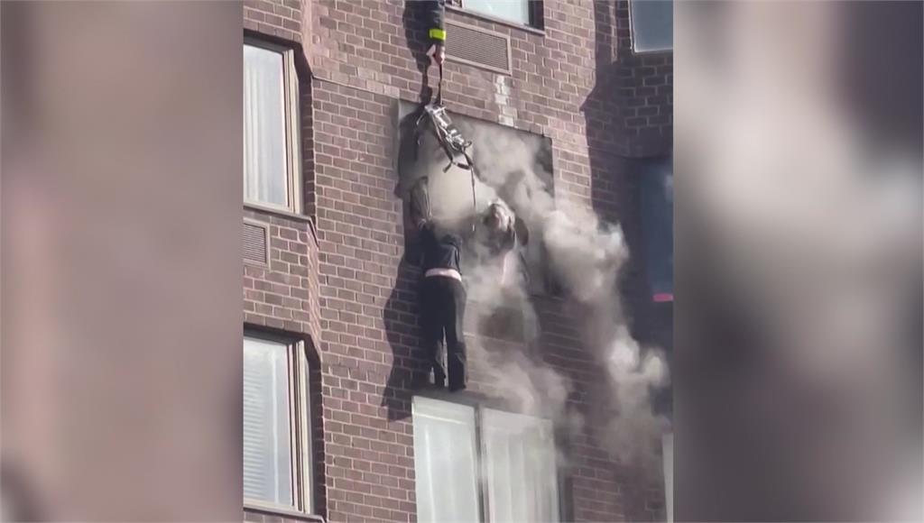 美國紐約市曼哈頓一棟公寓發生火災，住戶為了逃生一度攀爬垂掛在窗戶外。圖／路透社